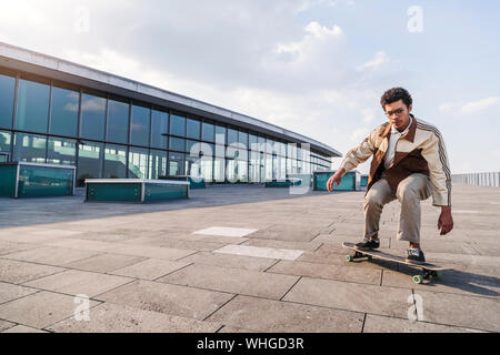 Focalizzato afro uomo scivola su skateboard su square Foto Stock