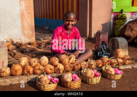 HAMPI, India - 21 febbraio 2012: il ragazzo non identificato di vendita offerte di noce di cocco per holi puja a Delhi, India Foto Stock
