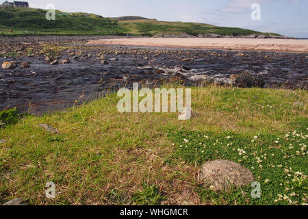 Una vista dal retro del Clashnessie bay, Sutherland, Scozia con il deflusso del fiume che scorre sulla spiaggia di rocce attraverso e intorno alla spiaggia Foto Stock