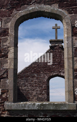 Una vista di una chiesa abbandonata di guardare attraverso una finestra sul frontone per altri gable end con una croce sulla parte superiore e Finestra opposta nel nord della Scozia Foto Stock