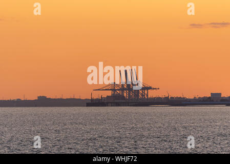 Tramonto dietro le gru portuali DP World London Gateway, Two Tree Island e Canvey Island da Southend Pier, Southend on Sea, Essex, Regno Unito Foto Stock