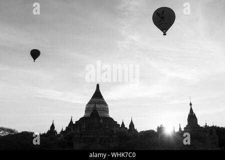 BAGAN, MYANMAR - 06 dicembre, 2018: foto in bianco e nero del cielo con i palloni ad aria calda e la silhouette di vecchi templi durante l'orario di alba in Baga Foto Stock