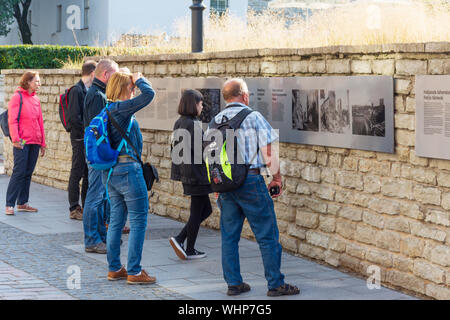 Turisti che guardano le targhe informative sul muro nella città vecchia di Tallinn Foto Stock