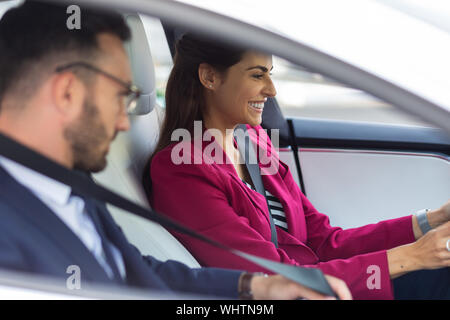 Imprenditrice sorridente mentre si guida auto con il marito seduti nelle vicinanze Foto Stock