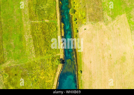 Bellissimo fiume Gacka che scorre tra gli alberi e i campi, summer view, Lika regione della Croazia, drone volando sopra la superficie del fiume Foto Stock