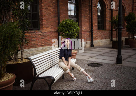 Giovane e bella viola hairy ragazza camminare al tramonto in un parco della città. San Pietroburgo, New Holland Foto Stock