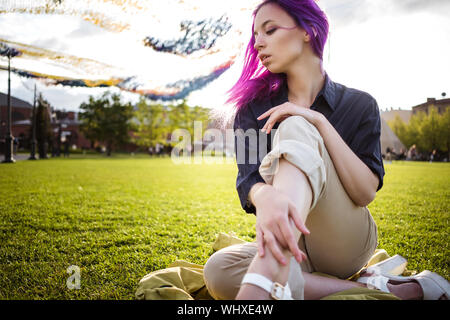 Giovane e bella viola hairy ragazza camminare al tramonto in un parco della città. San Pietroburgo, New Holland Foto Stock