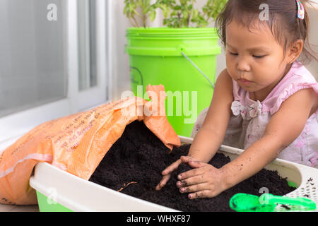 Una bambina di piantare semi nel suolo al di fuori nel giardino soleggiato. Foto Stock