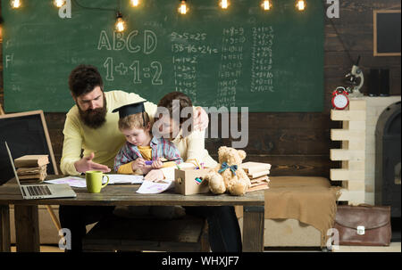 Concetto di homeschooling. I genitori insegna figlio, lavagna su sfondo. Ragazzo ascolto di mamma e papà con attenzione. I genitori insegnare kid, parlando. Fam Foto Stock