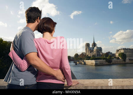 Vista posteriore di una coppia amorevole abbracciando davanti alla Cattedrale di Notre Dame Foto Stock