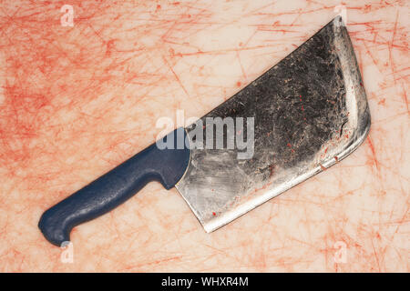 Primo piano di una sanguinosa cleaver sul bancone macchiata Foto Stock