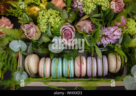 Amaretti nella casella di color turchese con fiori freschi. Eleganti colori in polvere. Alla vigilia del giorno della madre e la Giornata della donna Foto Stock