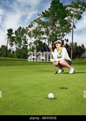 Lunghezza completa di deluso golfista femmina sul putting green Foto Stock