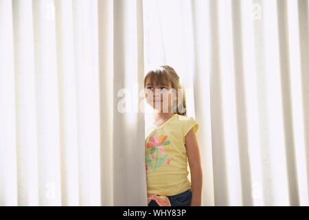 Premurosa bambina in piedi tra le tende Foto Stock