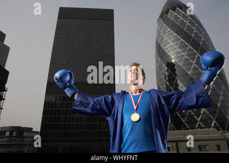 Boxer maschio che indossa la medaglia d'oro nella parte anteriore del centro cittadino di grattacieli in Londra Foto Stock