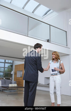 Maschio di agente immobiliare agitando felice mano di donna nuova casa Foto Stock