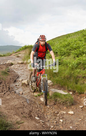 Vista di un maschio ciclista sulla campagna via fangose Foto Stock