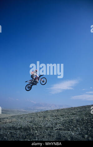 Basso angolo di visione di un uomo in mountain bike jumping contro il cielo blu Foto Stock