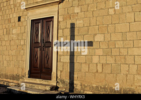 Ombra di una religiosa sulla croce la parete della chiesa Foto Stock