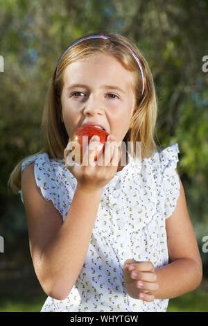 Closeup ritratto di una bambina di mangiare all'aperto apple Foto Stock