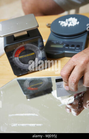 Immagine ritagliata di mano d'uomo preparando linee di cocaina con carta di credito sul mirror Foto Stock