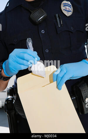 Close up dei maschi di funzionario di polizia holding pacchetto di farmaco e la busta Foto Stock