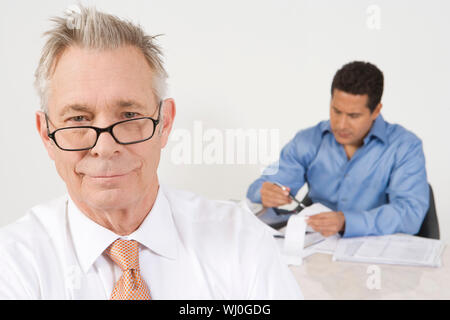Ritratto di imprenditore senior con il collega di sesso maschile lavora in background Foto Stock