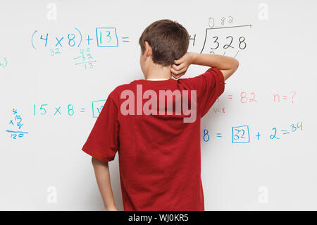 Scolaro in piedi contro la lavagna, vista posteriore Foto Stock