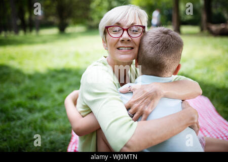 Felice la nonna con nipote abbracciando in un parco all'aperto Foto Stock