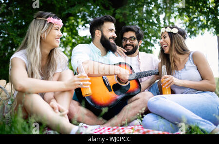 Estate, vacanze, la musica e il tempo libero concetto. Gruppo di amici hanno picnic all'aperto. Foto Stock