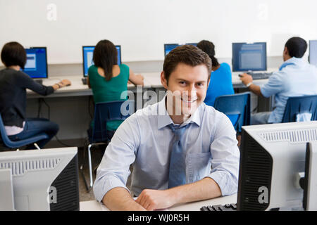 Ritratto di un felice di mezza età professore con gli studenti in laboratorio informatico Foto Stock