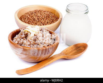 Disposizione dei tradizionali russi kasha di grano saraceno con grano saraceno in ciotola di legno, Vaso di latte e il cucchiaio di legno isolato su sfondo bianco Foto Stock