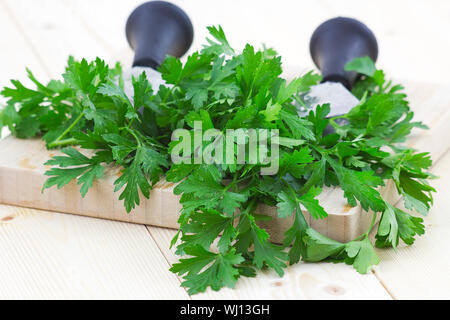 Prezzemolo tritato sul tagliere di legno Foto Stock