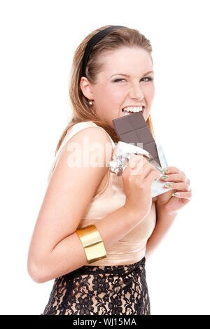 Ragazza giovane di mordere una barretta di cioccolato fondente su bianco isolato Foto Stock