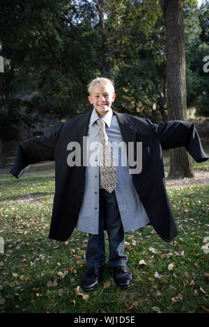 A piena lunghezza Ritratto di un sorridente ragazzo indossare tuta di grandi dimensioni all'aperto Foto Stock