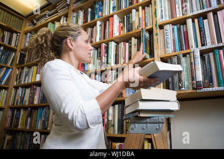 Bibliotecario femminile mettendo i libri sugli scaffali Foto Stock