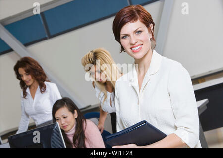 Ritratto di un sorridente imprenditrice con dirigenti multietnica dietro Foto Stock