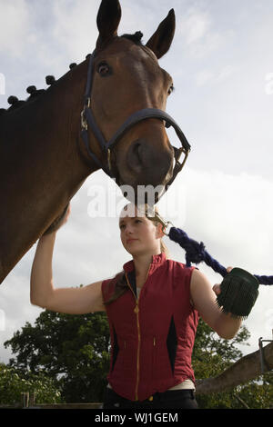 Giovane donna cavallo grooming all'aperto Foto Stock