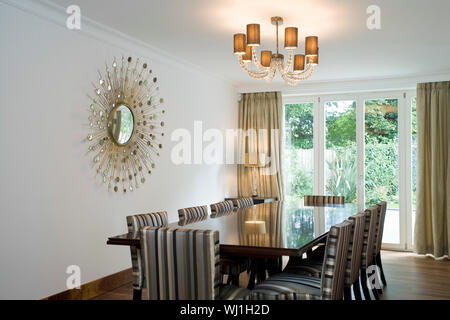 Vista di lit lampadario sopra il tavolo della sala da pranzo decorata con arte sulla parete di casa Foto Stock