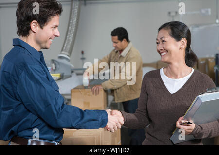 Multietnica l uomo e la donna si stringono la mano nel magazzino di distribuzione Foto Stock