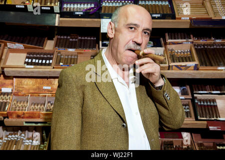 Ritratto di tabacco maturo proprietario di un negozio di sigari fumare in negozio Foto Stock