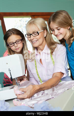 Ragazze cercando nonna panno di cucitura Foto Stock