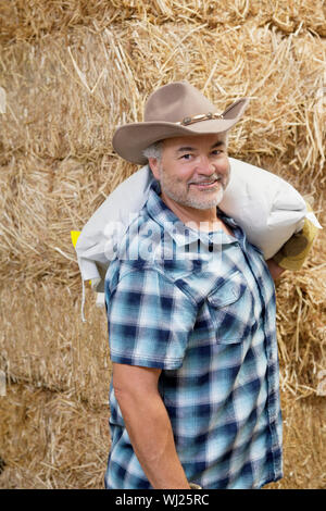 Ritratto di una felice coppia cowboy che trasportano il sacco sulla spalla Foto Stock