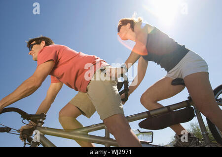 Basso angolo di visione di un giovane caucasico tandem di equitazione contro il cielo blu Foto Stock