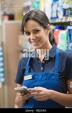 Ritratto di un supermercato sorridente impiegato femminile in grembiule blu Foto Stock