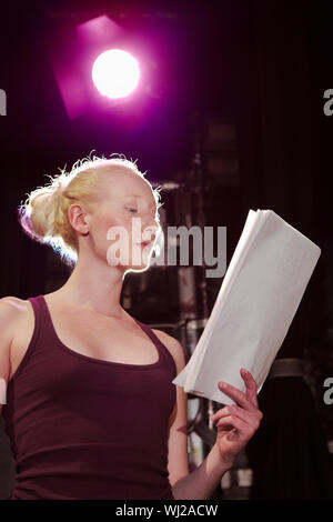 Basso angolo vista di una giovane donna di script di lettura sul palco Foto Stock