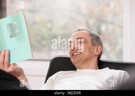 Rilassata uomo Libro di lettura a casa Foto Stock