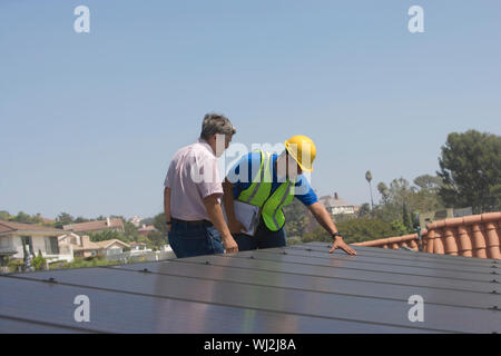 Lavoratori di manutenzione ispezione di pannelli solari sul tetto Foto Stock