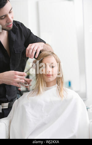 Bella donna getting taglio di capelli da parrucchiere maschio al salone di bellezza Foto Stock
