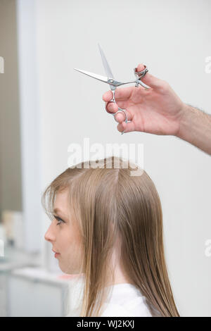 Vista laterale della giovane donna getting haircut presso il salone di bellezza Foto Stock